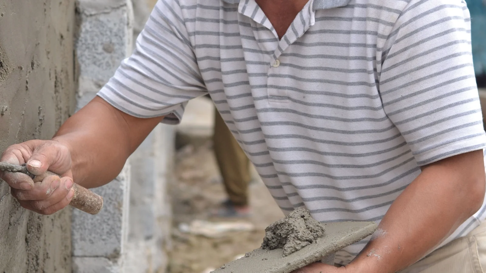 Mason repairing a stucco corner and applying a new plaster edge